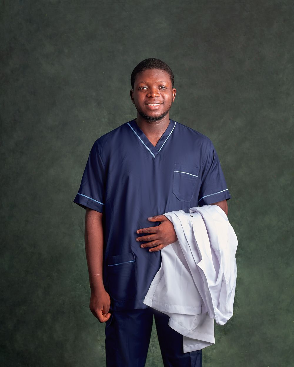 Illustrative stock portrait of a smiling Black male care professional in blue scrubs